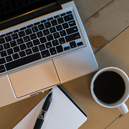 An overhead view of a desk with a laptop coffee cup and a pen